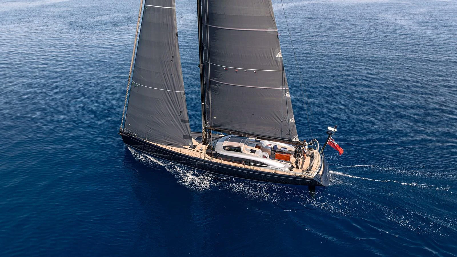 A sleek sailing yacht glides gracefully over calm blue waters. aboard CAIAROSSA Yacht for Sale