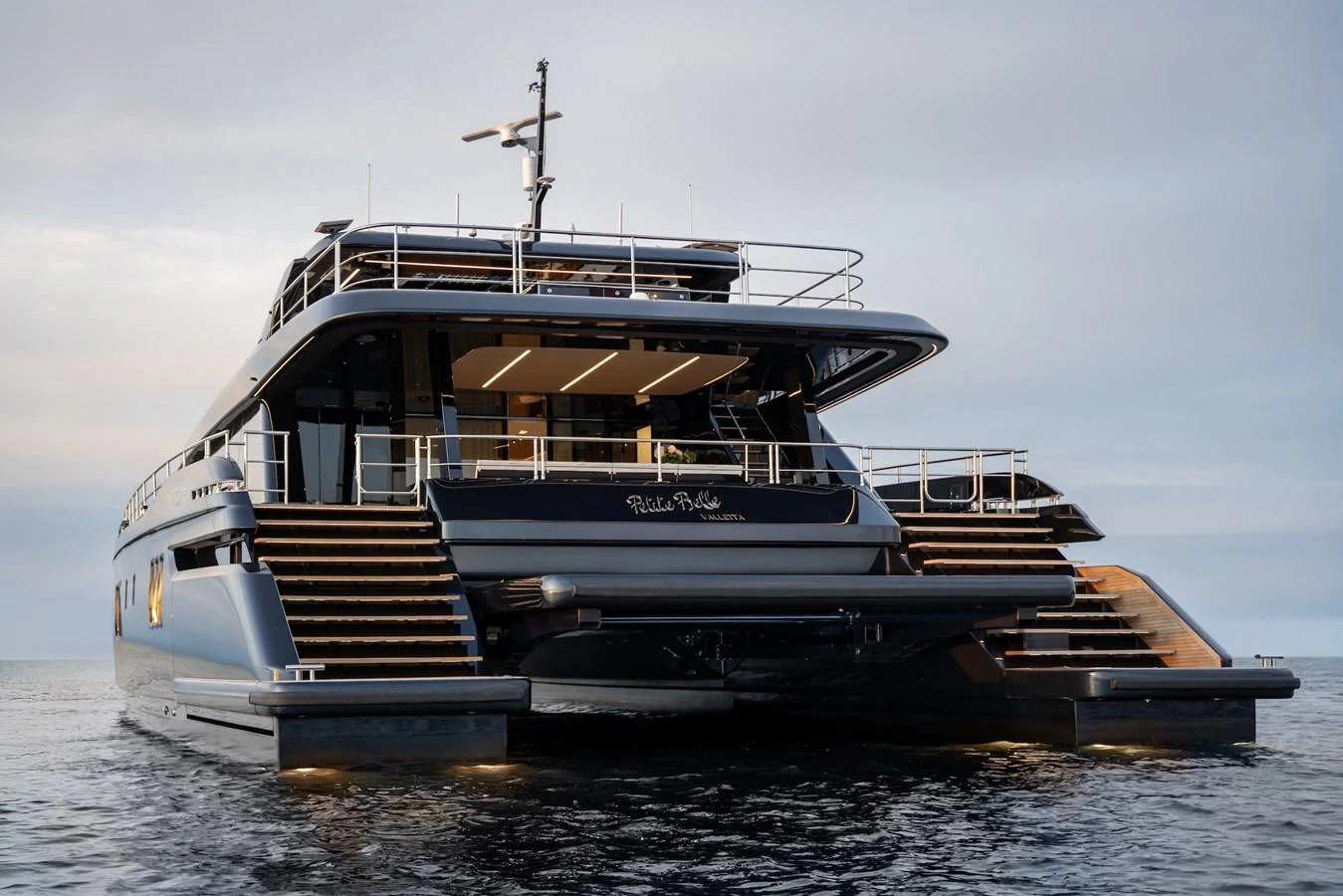 A luxurious yacht with sleek design and modern amenities, captured from the rear on calm waters. aboard PETITE BELLE Yacht for Sale
