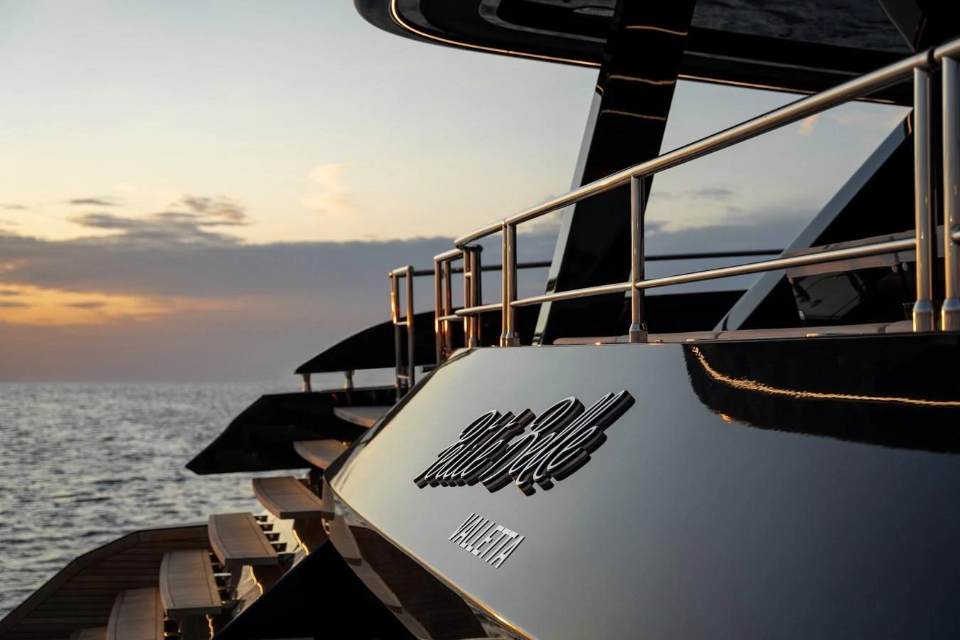 The yacht's sleek exterior is beautifully highlighted against a serene sunset backdrop. aboard PETITE BELLE Yacht for Sale