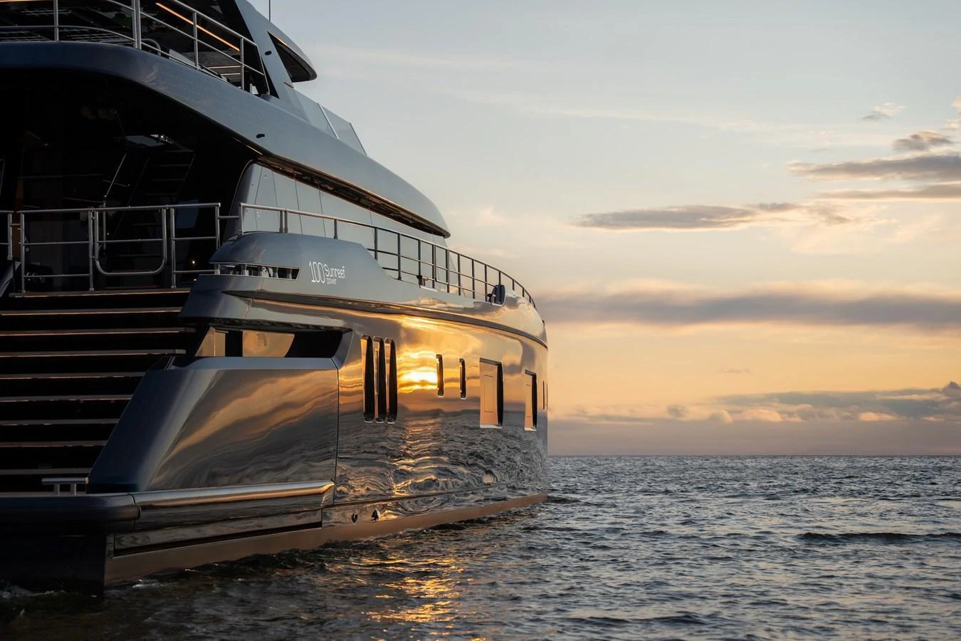 The yacht glides gracefully on the water at sunset, reflecting the golden hues of the sky. aboard PETITE BELLE Yacht for Sale
