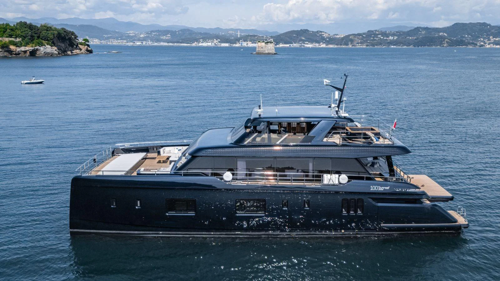A sleek and modern yacht cruising on calm waters with a scenic coastline in the background. aboard PETITE BELLE Yacht for Sale