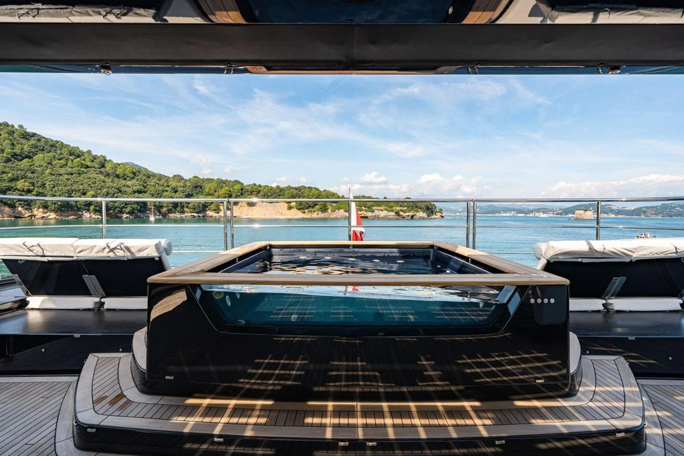 A luxurious pool deck with stunning views of the surrounding waters and landscape. aboard PETITE BELLE Yacht for Sale