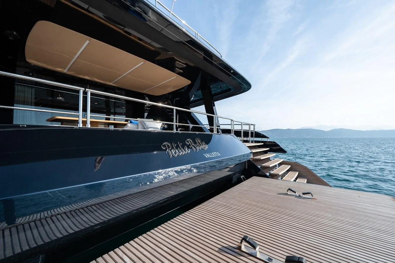 The yacht's sleek aft deck features a spacious swim platform and elegant design details. aboard PETITE BELLE Yacht for Sale