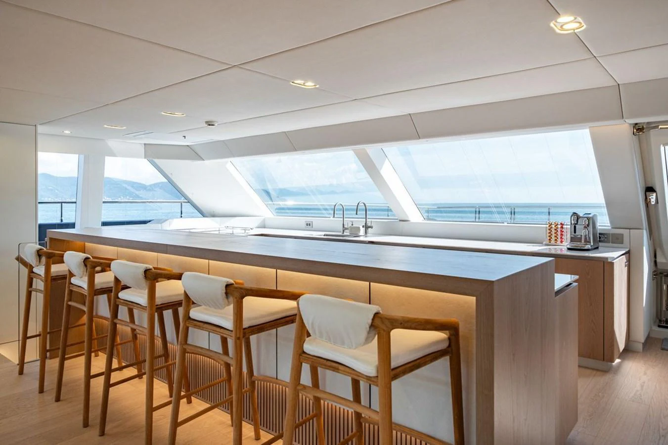 The yacht's galley features a sleek, modern design with ample seating and panoramic windows offering stunning ocean views. aboard PETITE BELLE Yacht for Sale