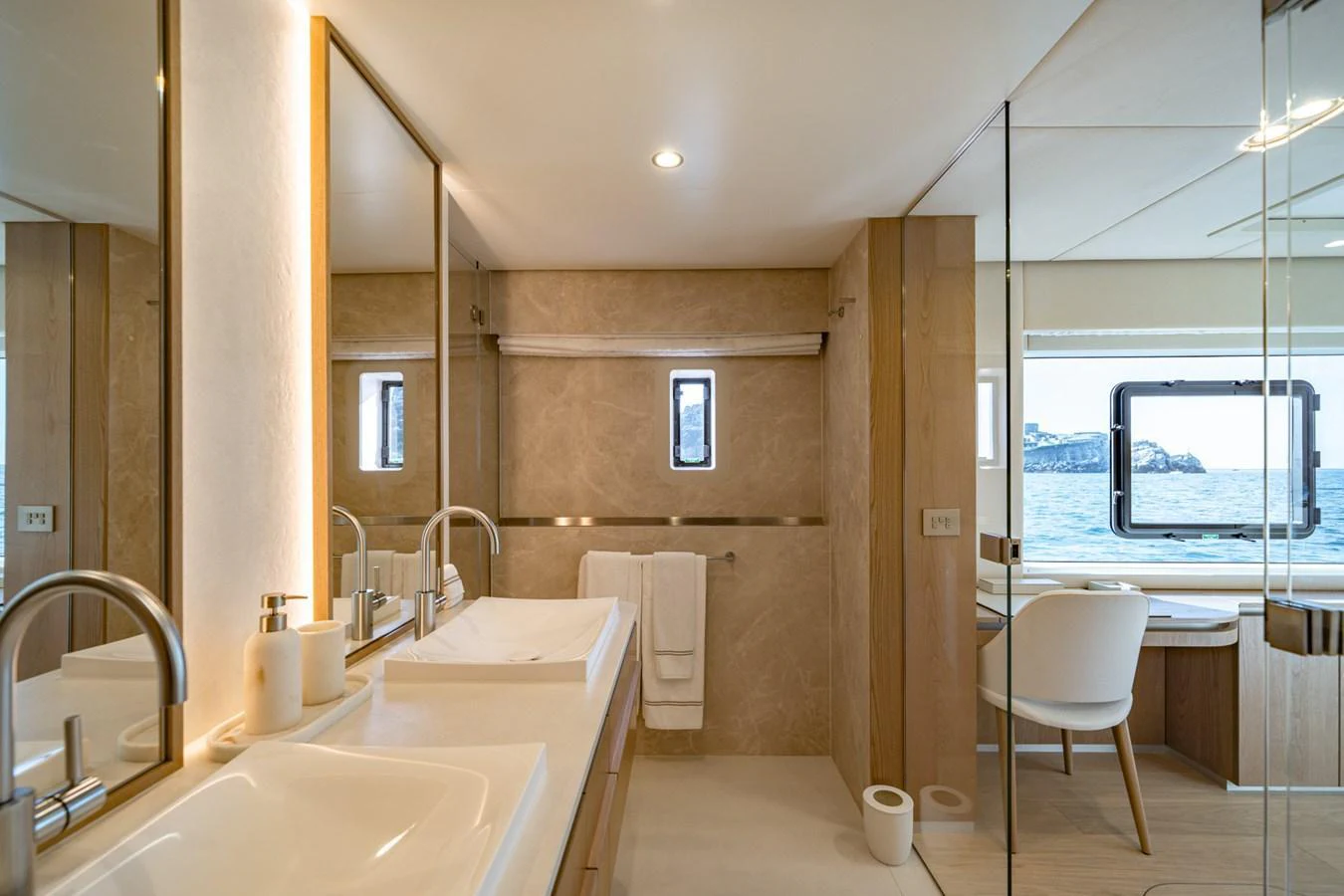 The yacht's bathroom features a luxurious design with dual sinks, a large mirror, and a scenic ocean view. aboard PETITE BELLE Yacht for Sale