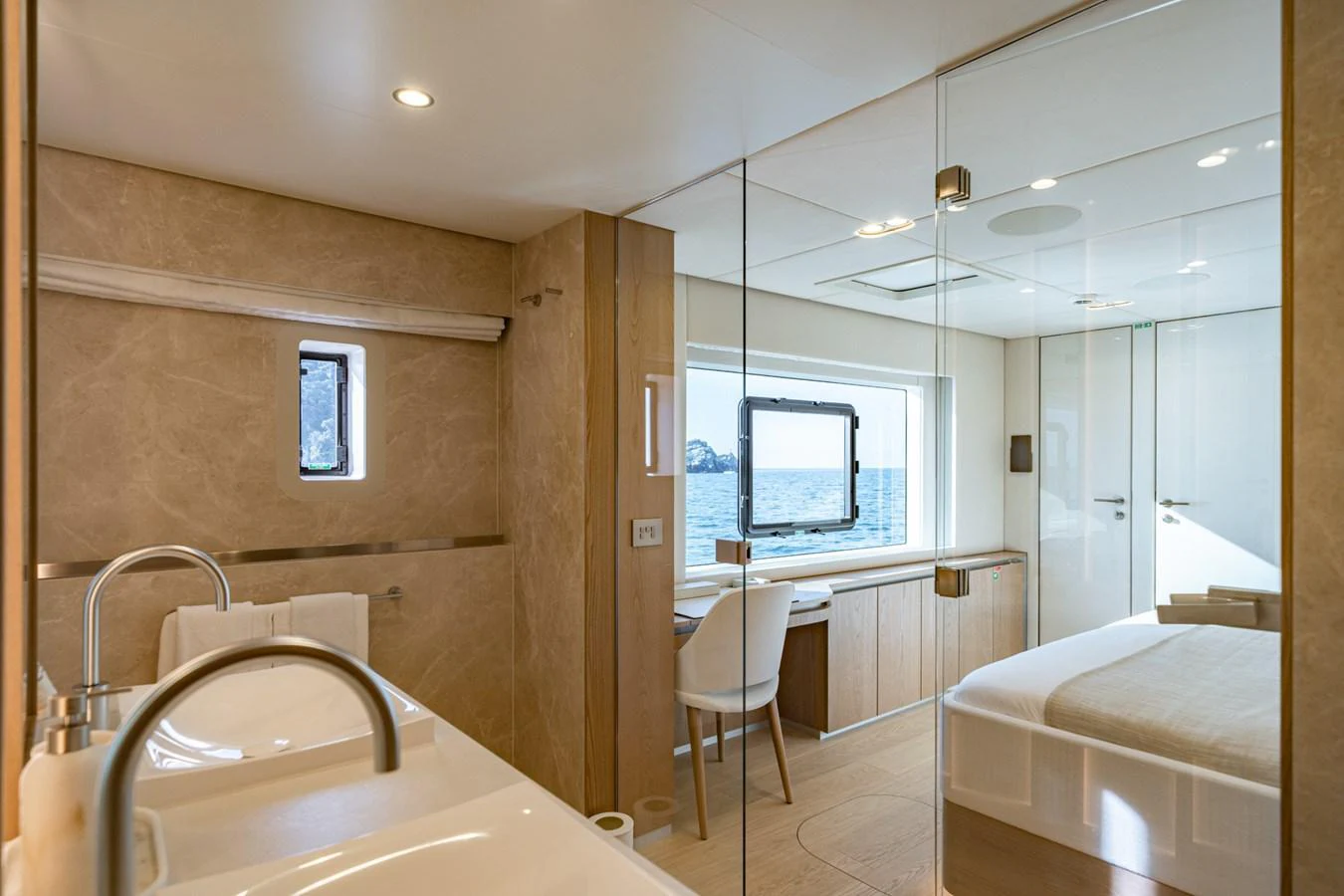 The stateroom features a luxurious bed, a desk with a view, and a modern ensuite bathroom. aboard PETITE BELLE Yacht for Sale