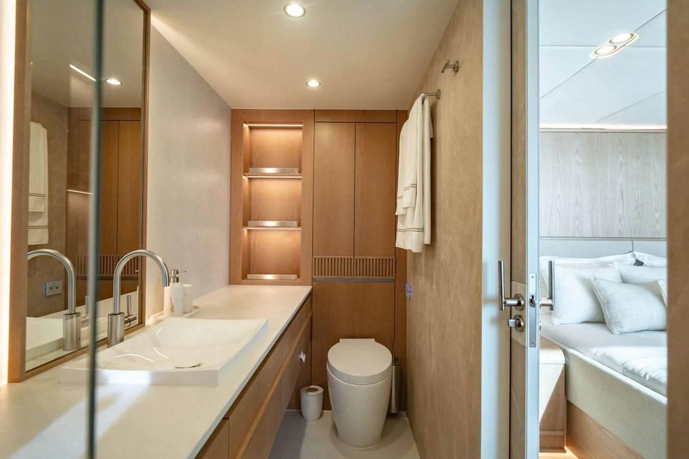 A modern yacht bathroom with sleek fixtures and a view into the adjacent stateroom. aboard PETITE BELLE Yacht for Sale
