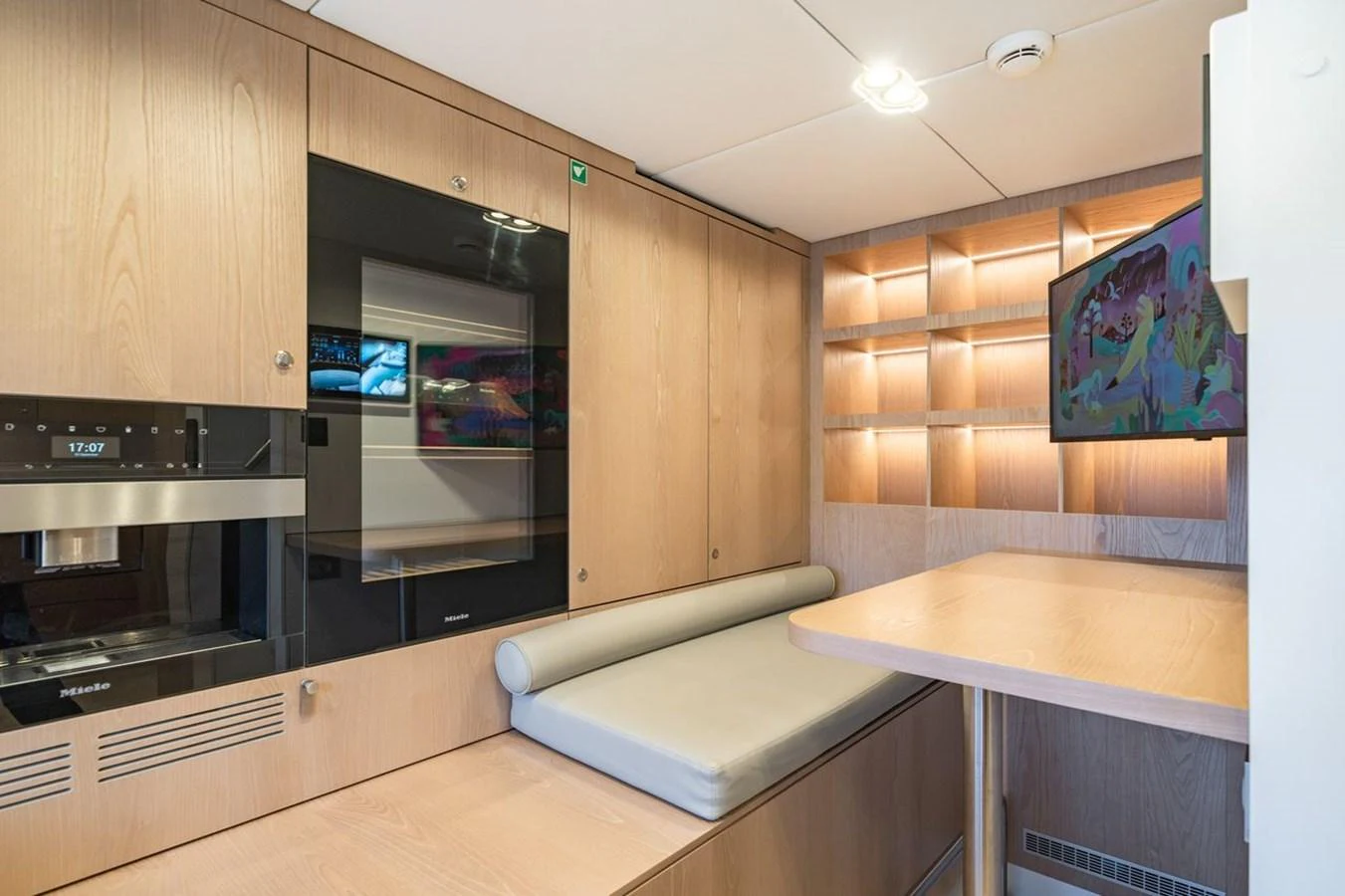The yacht's galley features modern appliances and a cozy dining area with a mounted TV. aboard PETITE BELLE Yacht for Sale