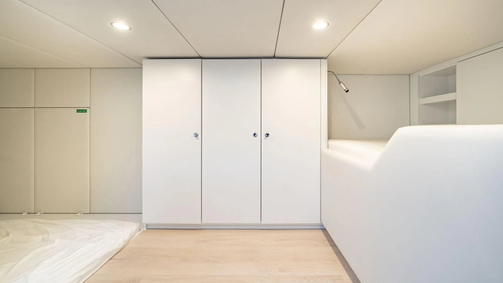 The yacht's interior features a minimalist design with white cabinetry and light wood flooring. aboard PETITE BELLE Yacht for Sale