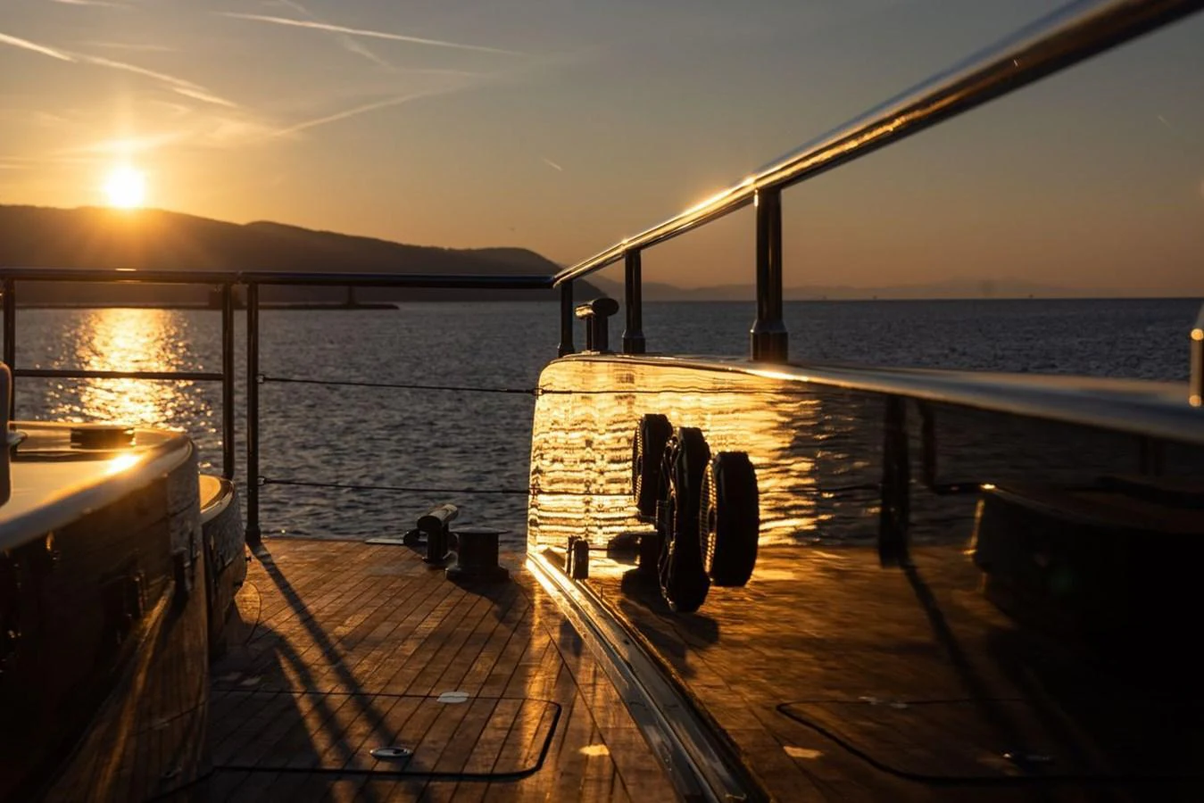 The yacht's deck is bathed in the warm glow of a sunset over the water. aboard PETITE BELLE Yacht for Sale