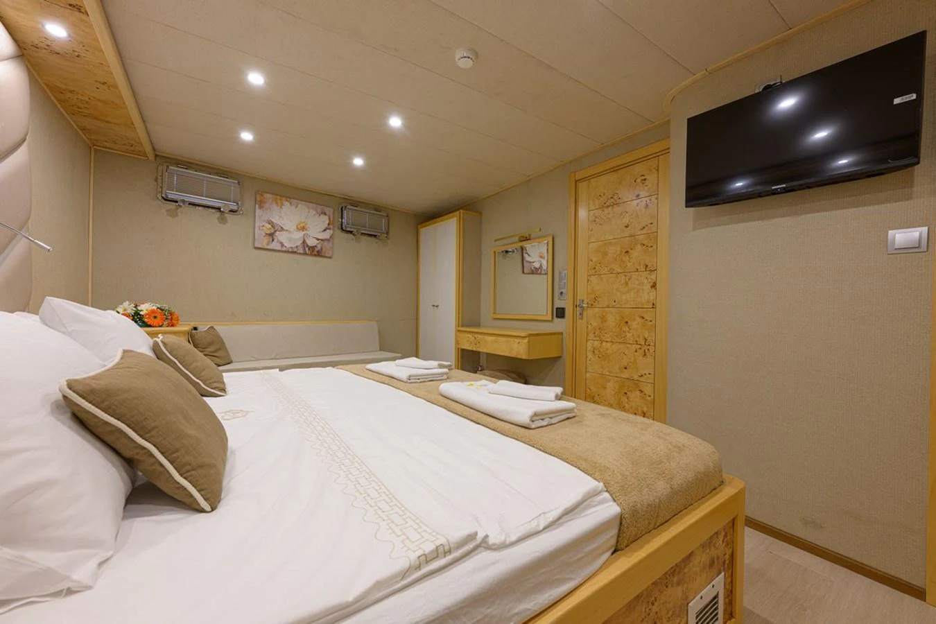 The stateroom features a comfortable bed, a wall-mounted TV, and a cozy seating area. aboard BELGIN SULTAN Yacht for Sale
