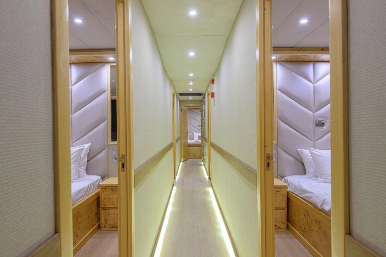 A well-lit hallway with cozy twin beds on either side, leading to another section of the yacht. aboard BELGIN SULTAN Yacht for Sale