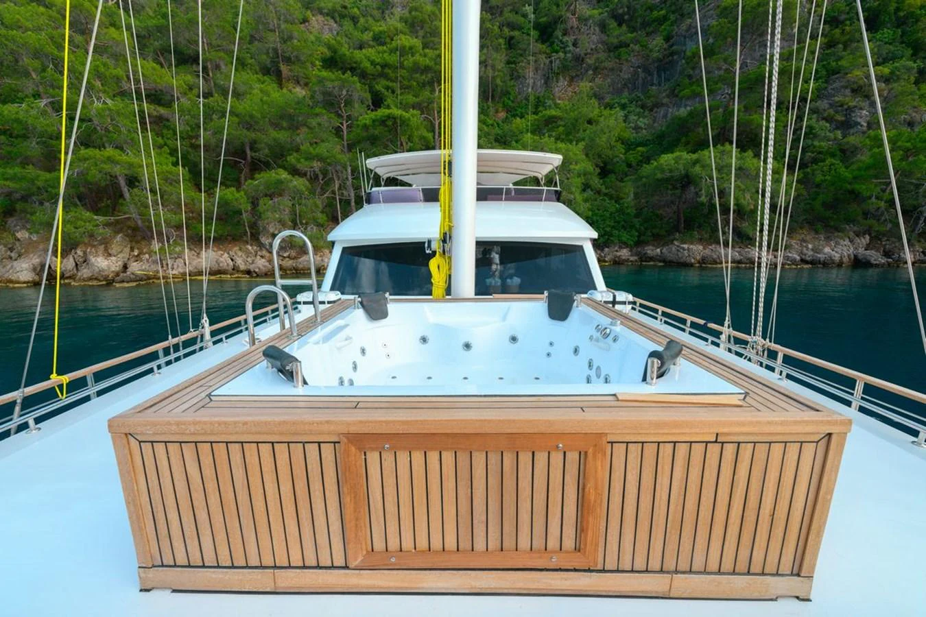 The yacht features a luxurious deck jacuzzi with a scenic backdrop of lush greenery and calm waters. aboard BELGIN SULTAN Yacht for Sale