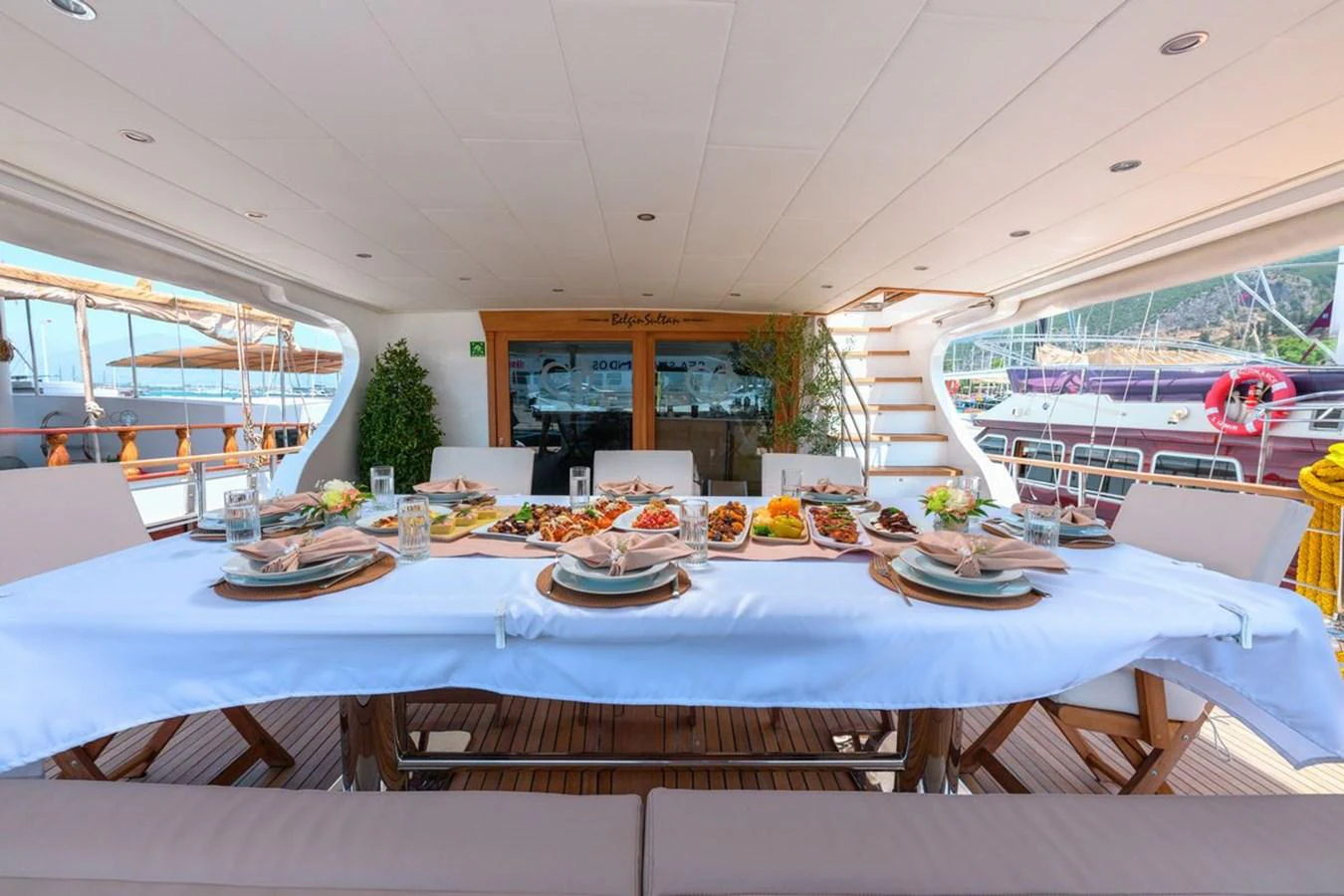The aft deck features an elegant dining area set for a meal, offering a perfect spot for alfresco dining. aboard BELGIN SULTAN Yacht for Sale