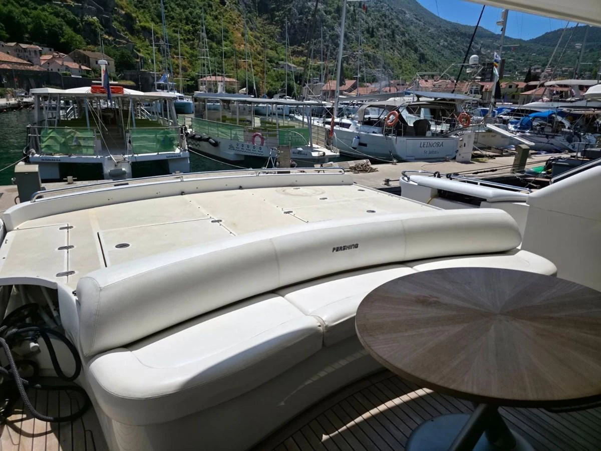 The aft deck features a comfortable seating area with a sleek wooden table, perfect for enjoying the marina views. aboard EVASIONE Yacht for Sale