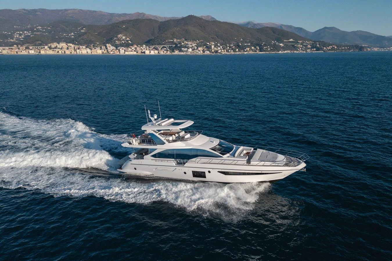 A sleek and modern yacht cruising on the open water with a scenic coastal backdrop. aboard HELSIE SI Yacht for Sale