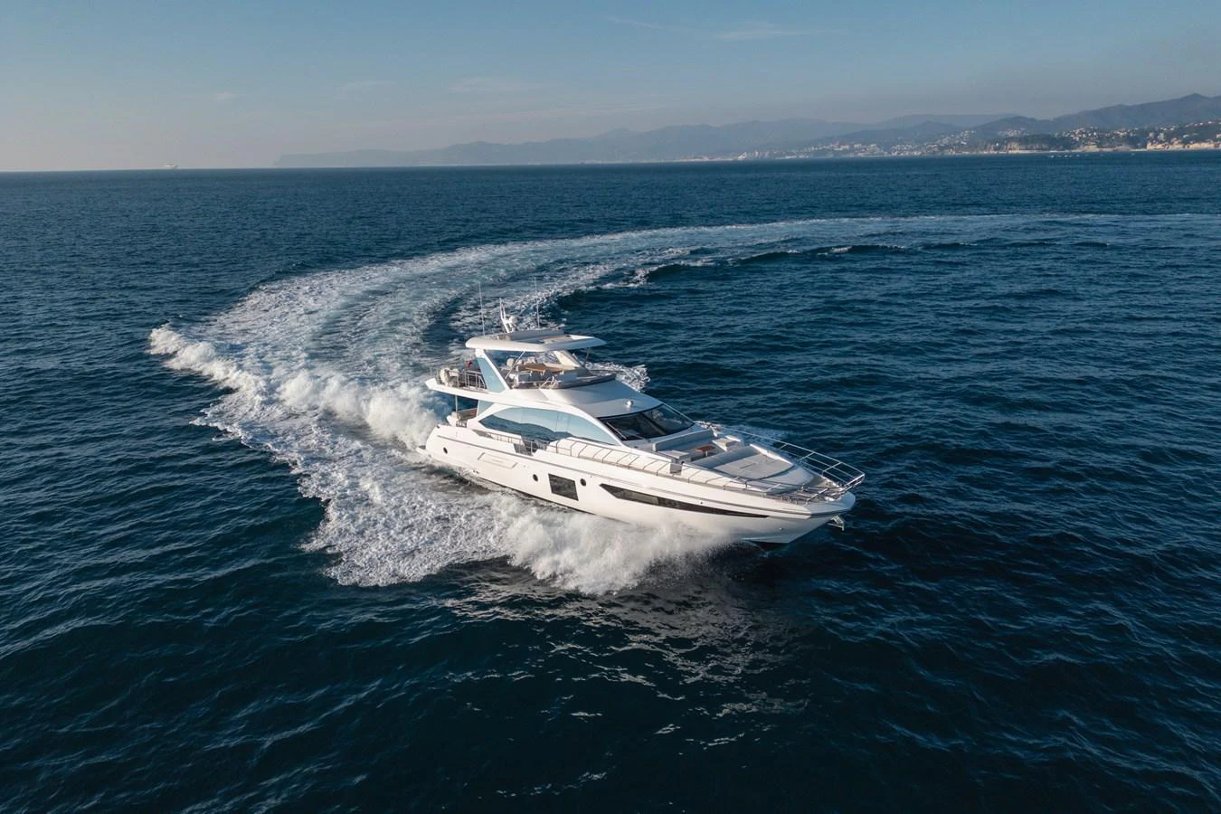 A sleek and modern yacht glides swiftly across the open sea, leaving a trail of white foam in its wake. aboard HELSIE SI Yacht for Sale