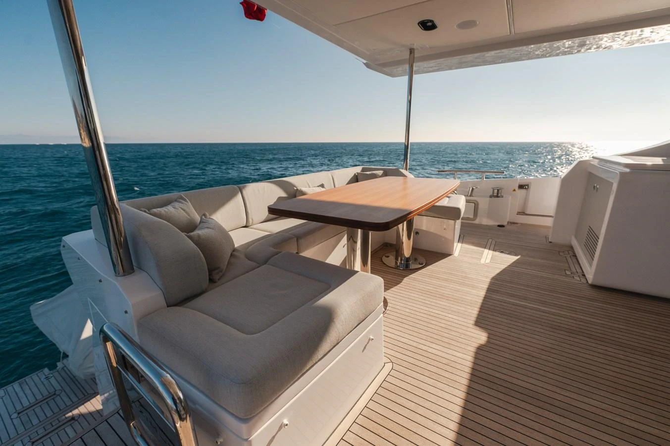 The aft deck features a comfortable seating area with a wooden table, perfect for enjoying the ocean views. aboard HELSIE SI Yacht for Sale