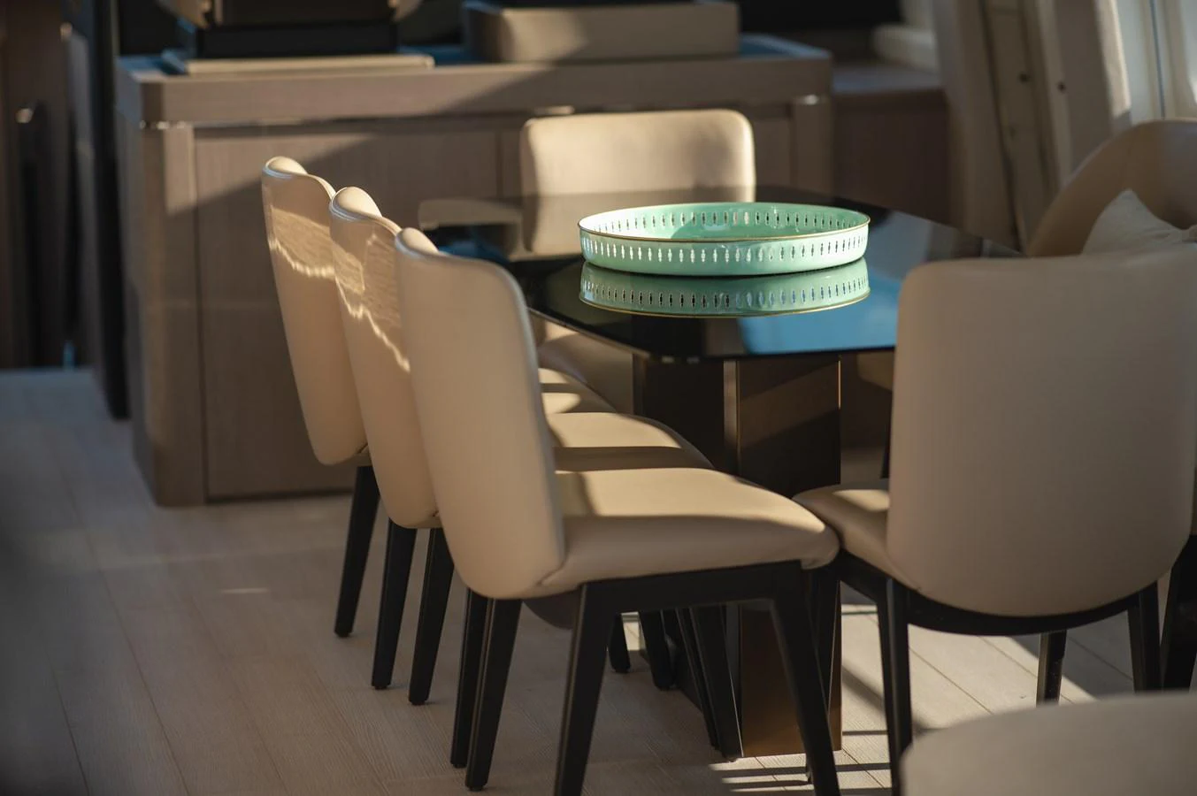 The yacht's dining area features a sleek black table surrounded by comfortable beige chairs, creating an inviting space for meals. aboard HELSIE SI Yacht for Sale