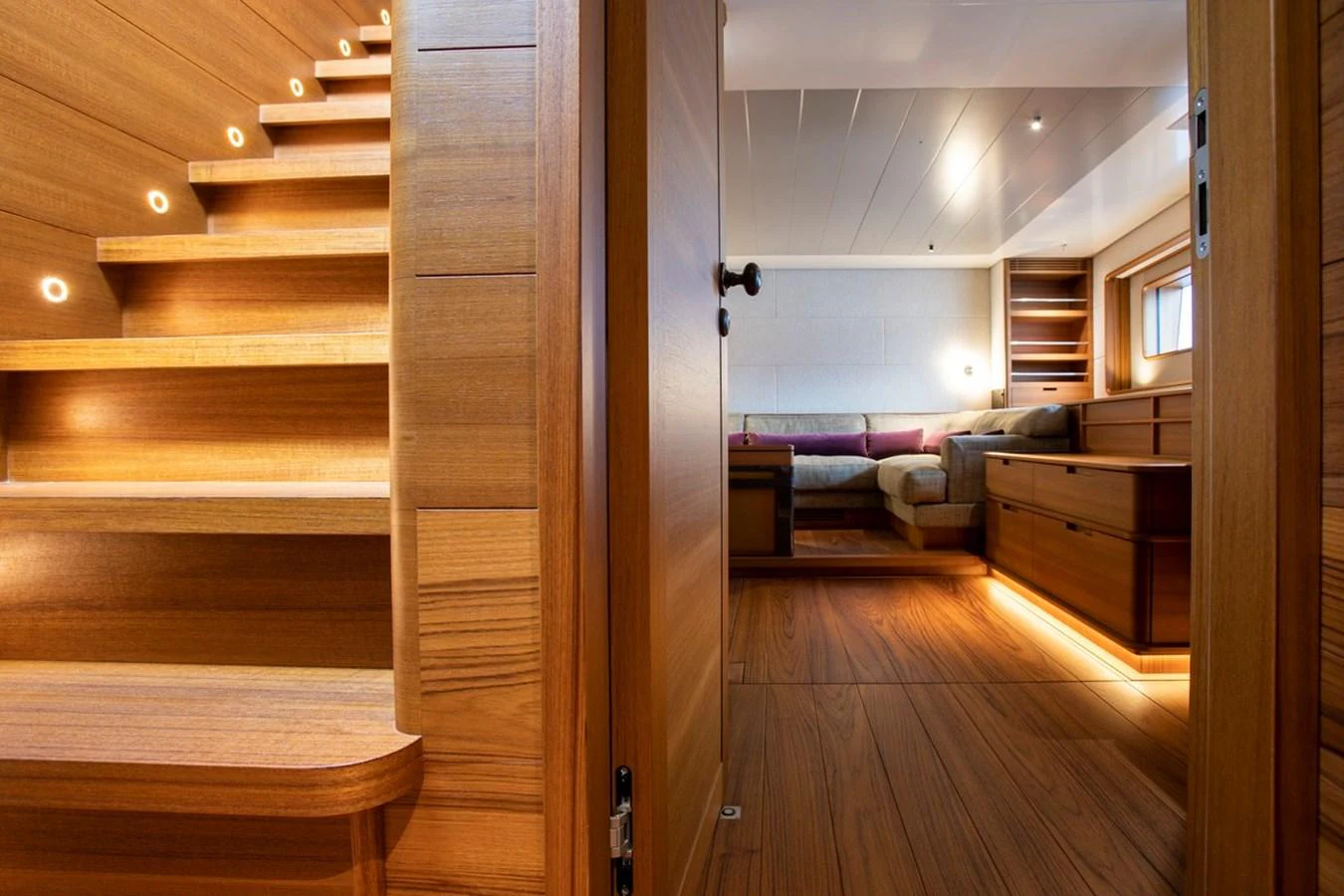 The image showcases a luxurious interior with a wooden staircase leading to a cozy lounge area. aboard CANOVA Yacht for Sale