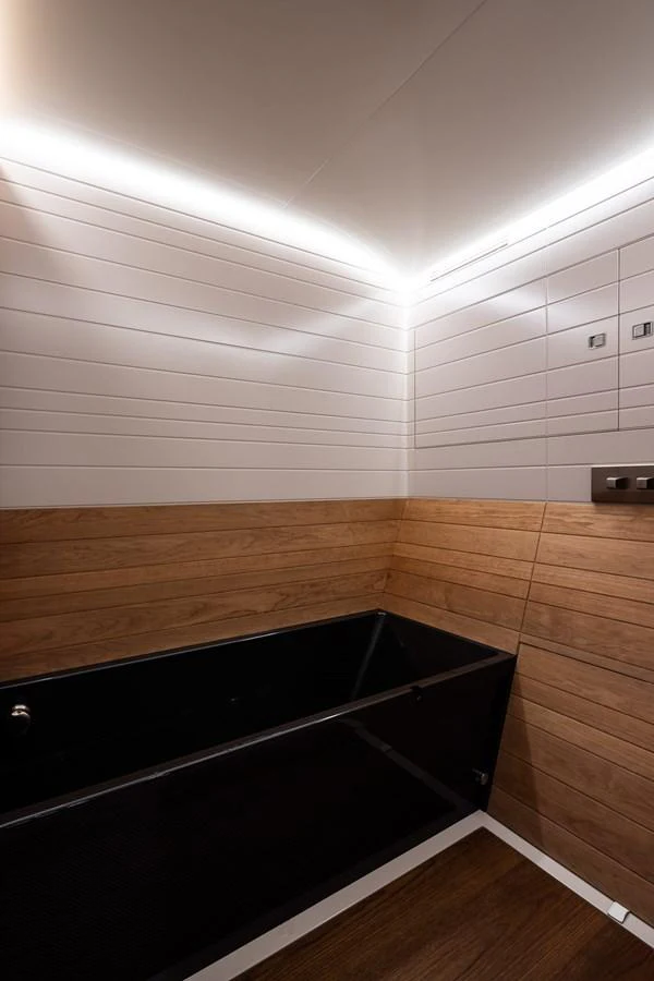A sleek and modern yacht bathroom featuring wood paneling and a black bathtub. aboard CANOVA Yacht for Sale