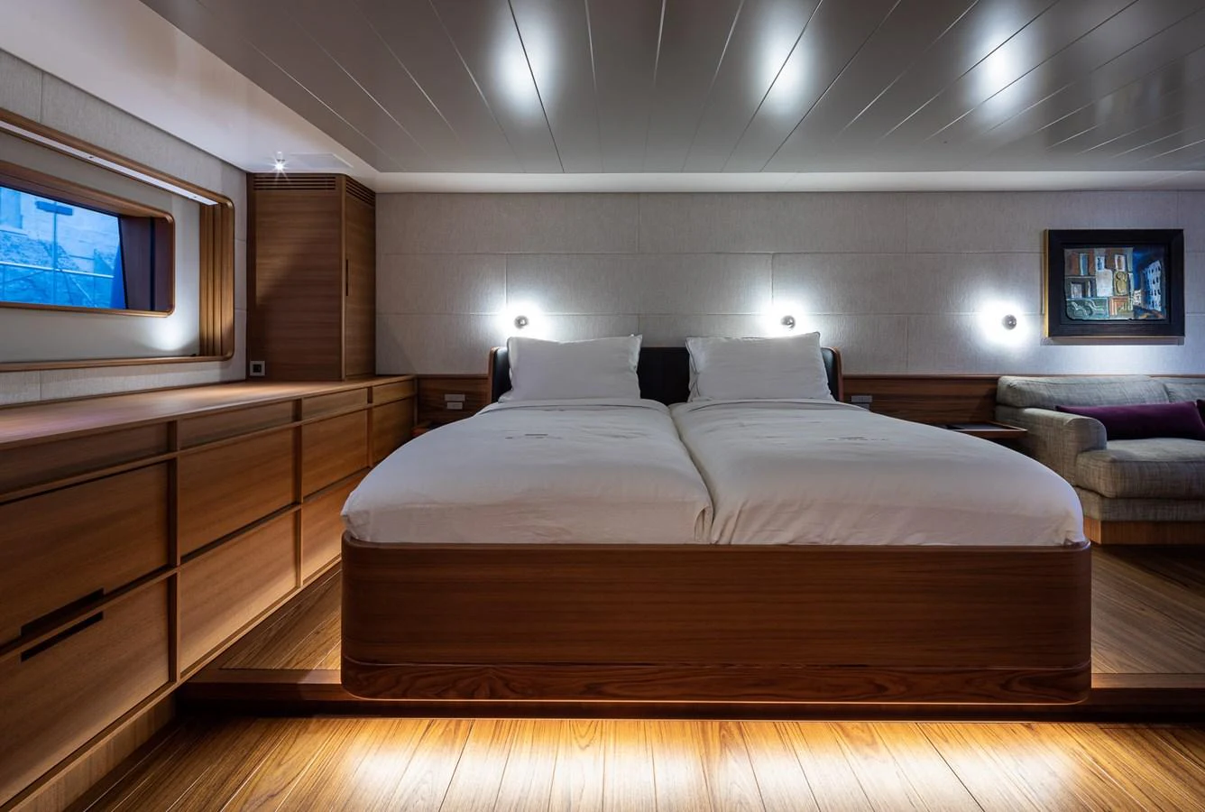 The stateroom features a luxurious double bed with elegant wood paneling and ambient lighting. aboard CANOVA Yacht for Sale