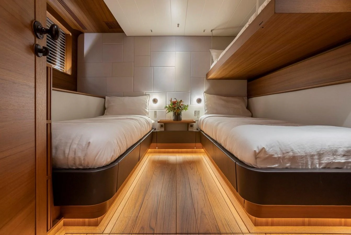 The twin stateroom features modern design with warm wood tones and ambient lighting. aboard CANOVA Yacht for Sale