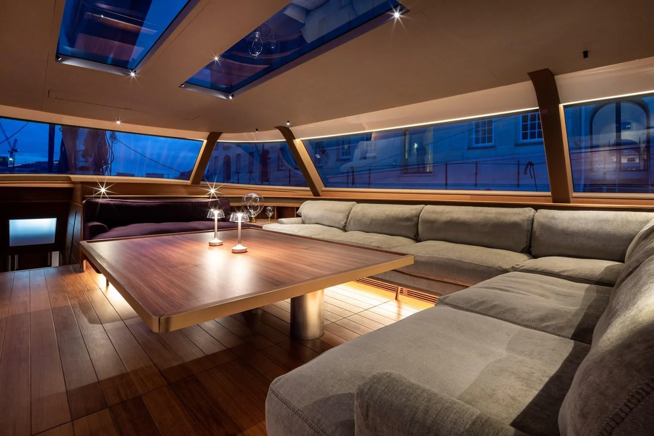 The salon features a spacious seating area with a large wooden table and ample natural light from overhead skylights. aboard CANOVA Yacht for Sale