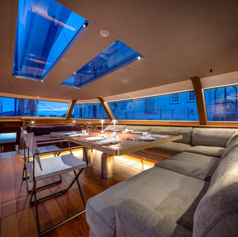 The yacht's dining area features a modern table setup with ample seating and large windows providing a stunning view. aboard CANOVA Yacht for Sale