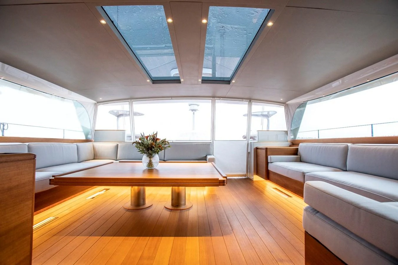 The salon features elegant wood flooring, plush seating, and ample natural light from overhead skylights. aboard CANOVA Yacht for Sale