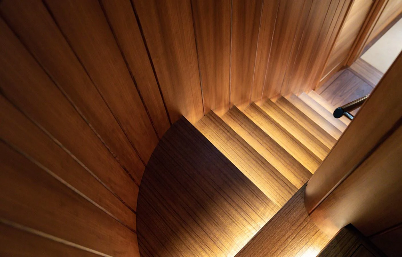 A beautifully crafted wooden staircase with warm lighting. aboard CANOVA Yacht for Sale