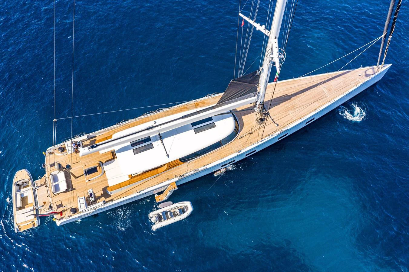 A sleek sailing yacht glides through the deep blue sea, showcasing its elegant design from an aerial perspective. aboard CANOVA Yacht for Sale