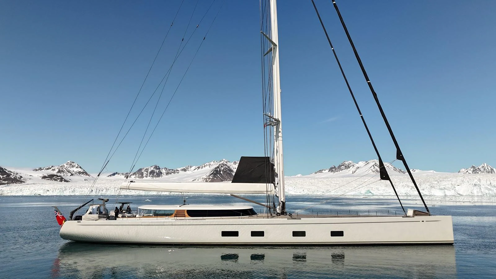 A sleek sailing yacht glides gracefully on calm waters with a stunning icy mountain backdrop. aboard CANOVA Yacht for Sale