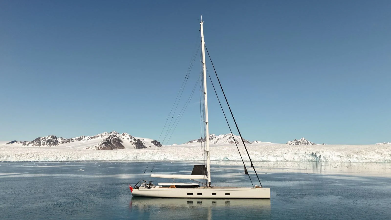 A sleek yacht sails gracefully in serene icy waters with a backdrop of snow-capped mountains. aboard CANOVA Yacht for Sale