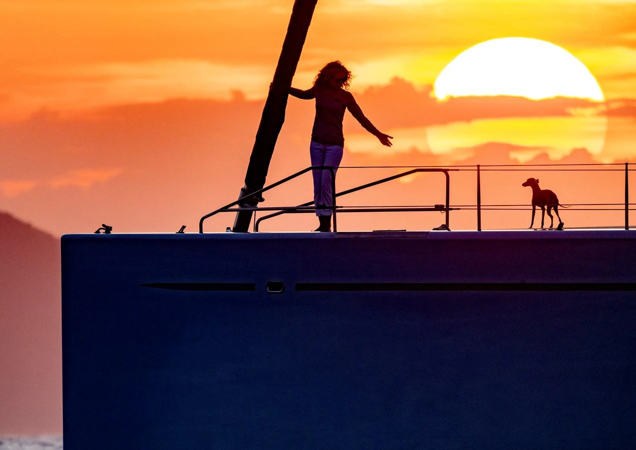 A person and a dog enjoy the sunset on the deck of a yacht. aboard CANOVA Yacht for Sale