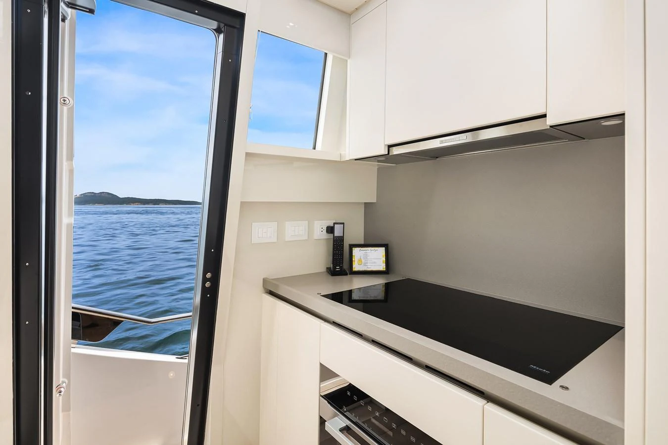 The sleek and modern galley offers a stunning view of the water through a side window. aboard ESSENZA Yacht for Sale