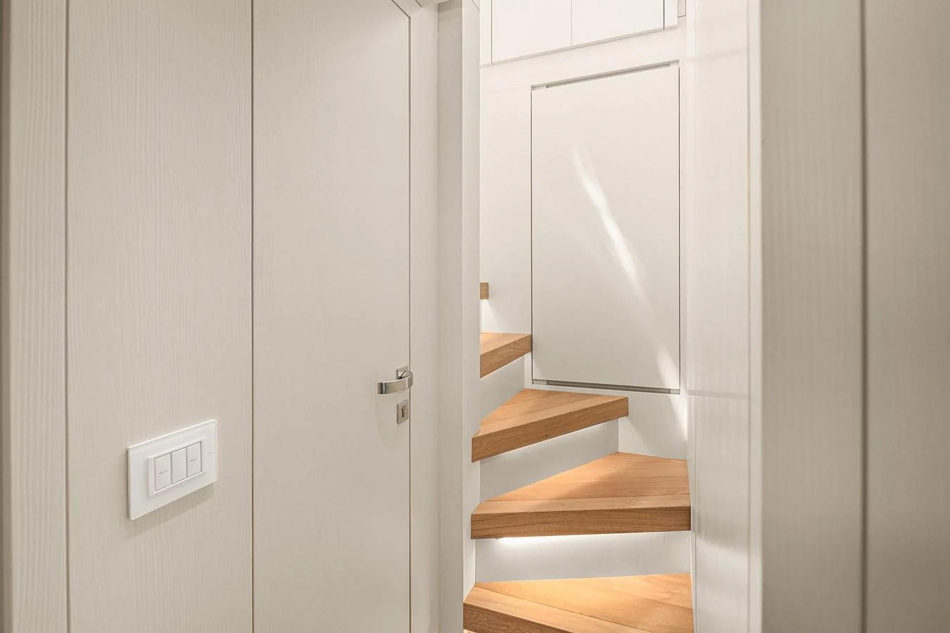 A modern and sleek interior staircase with wooden steps and white walls. aboard ESSENZA Yacht for Sale