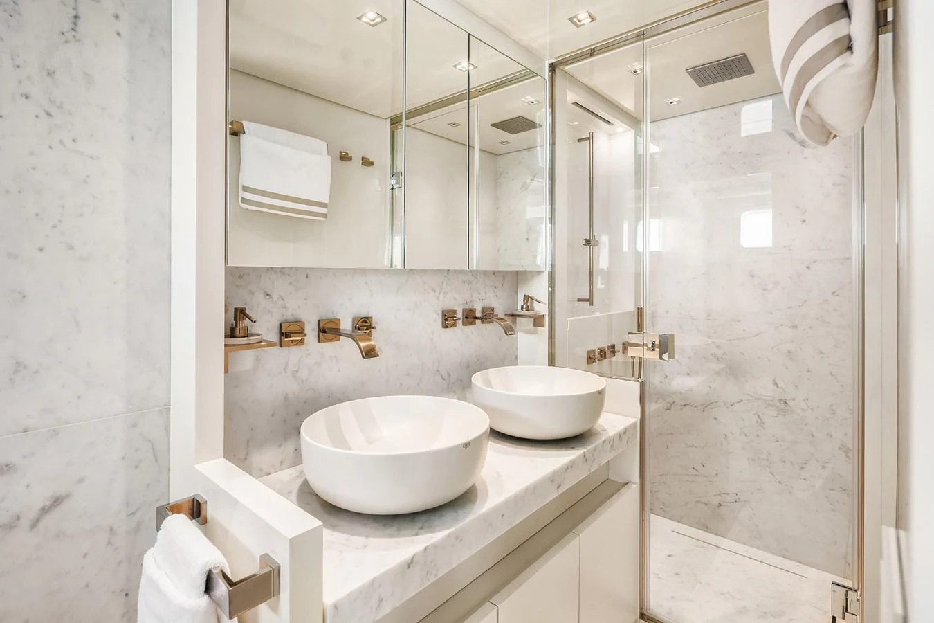 The yacht's bathroom features a luxurious marble design with dual sinks and a spacious shower area. aboard ESSENZA Yacht for Sale