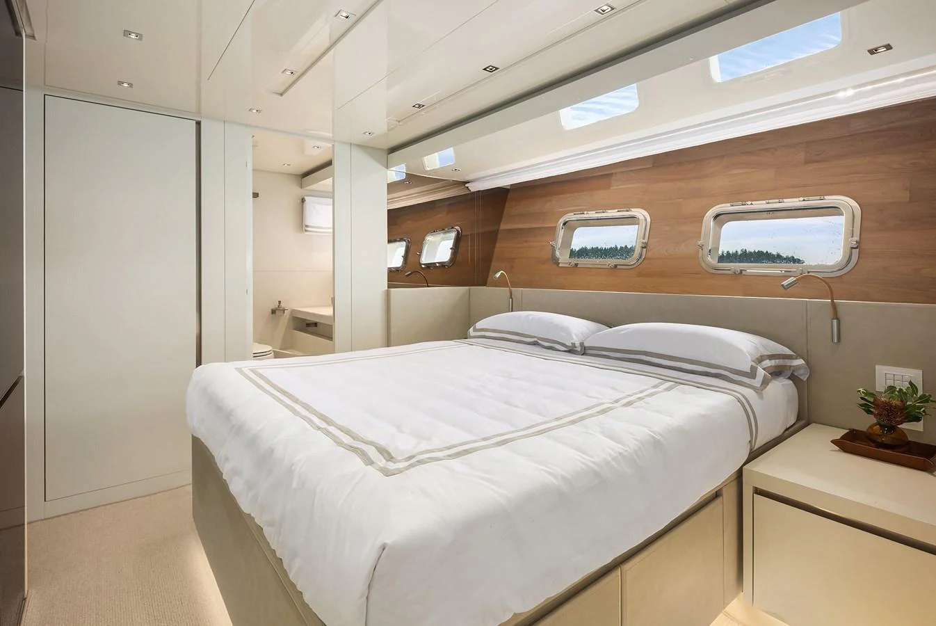 The stateroom features a luxurious bed with elegant linens and ample natural light from the windows. aboard ESSENZA Yacht for Sale