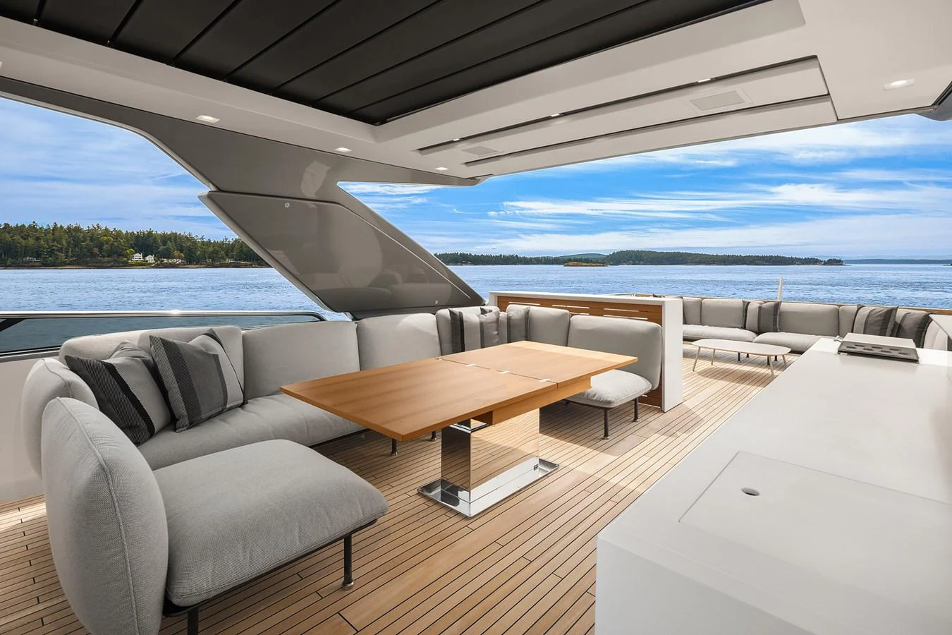 The aft deck features a spacious seating area with a wooden table, offering stunning views of the water. aboard ESSENZA Yacht for Sale