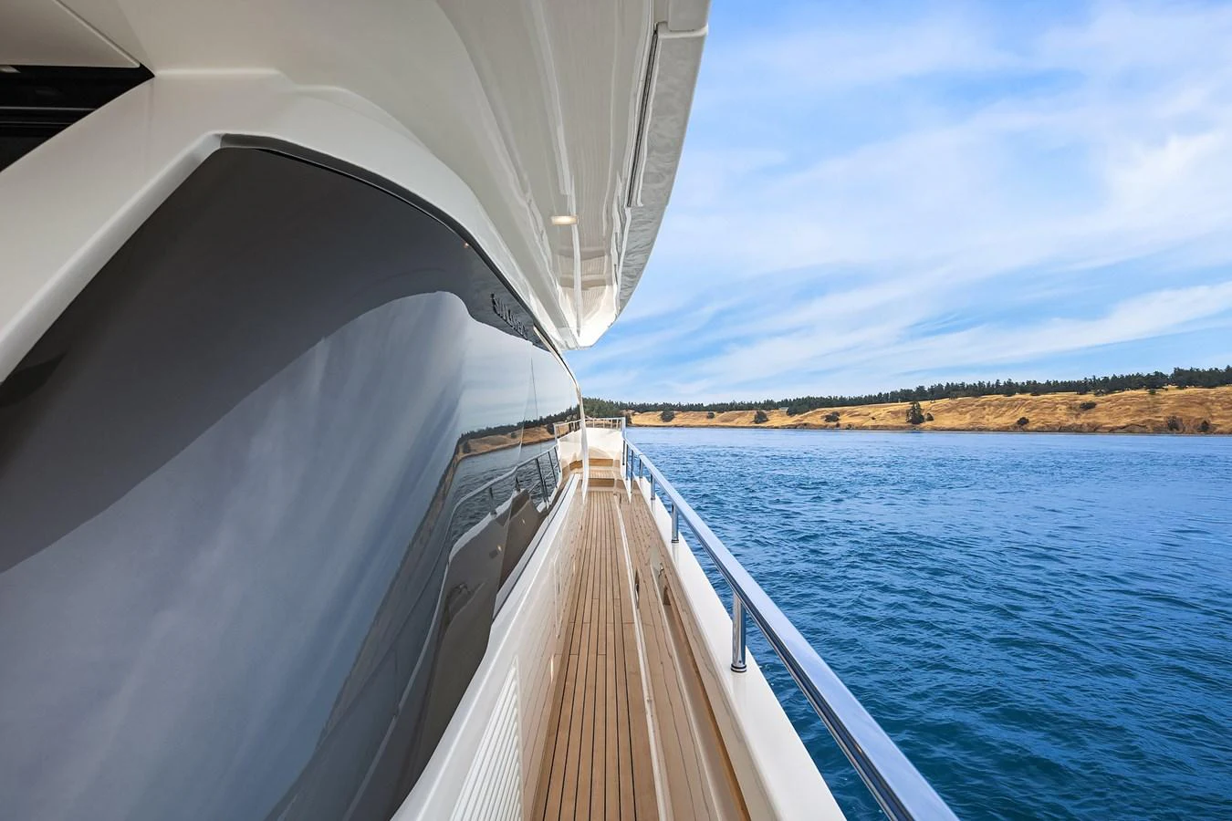 The sleek side deck of the yacht offers a stunning view of the water and shoreline. aboard ESSENZA Yacht for Sale