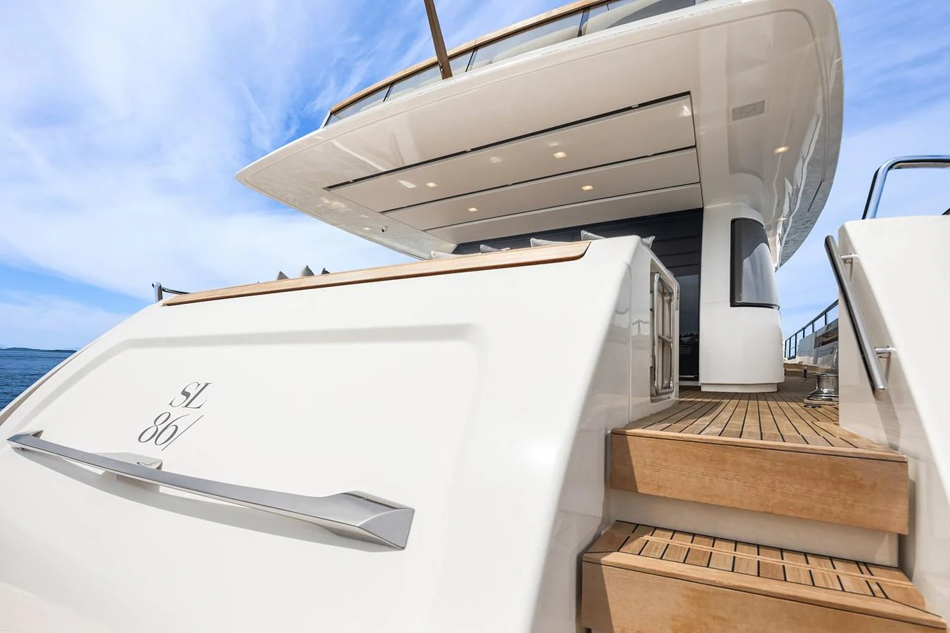 The yacht's aft deck features elegant teak steps leading up to a spacious and modern outdoor area. aboard ESSENZA Yacht for Sale
