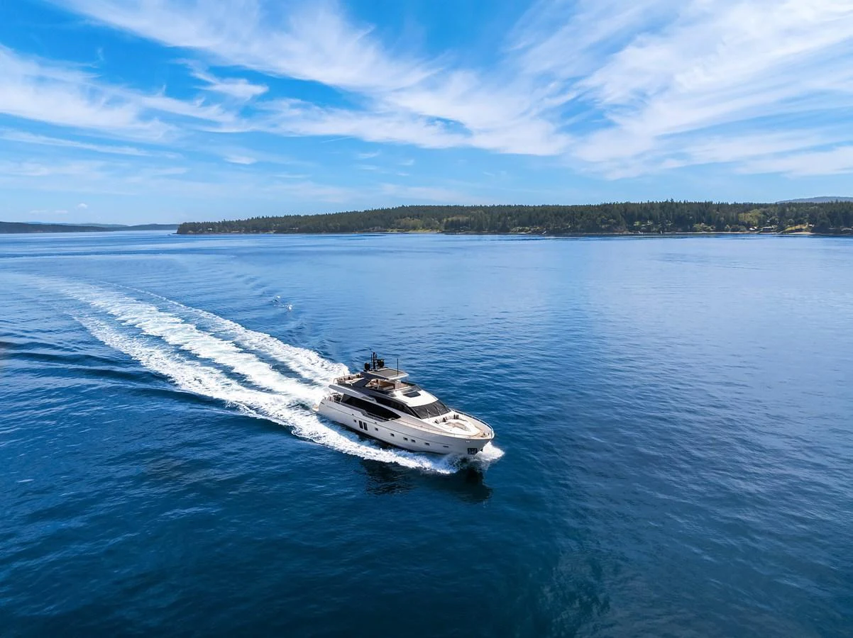 A sleek yacht cruises through calm blue waters under a clear sky. aboard ESSENZA Yacht for Sale
