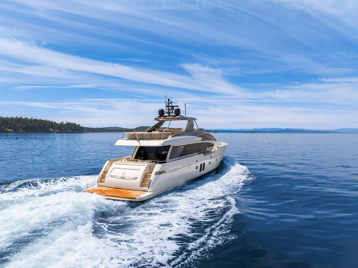 A sleek yacht cruises through calm waters under a clear blue sky. aboard ESSENZA Yacht for Sale
