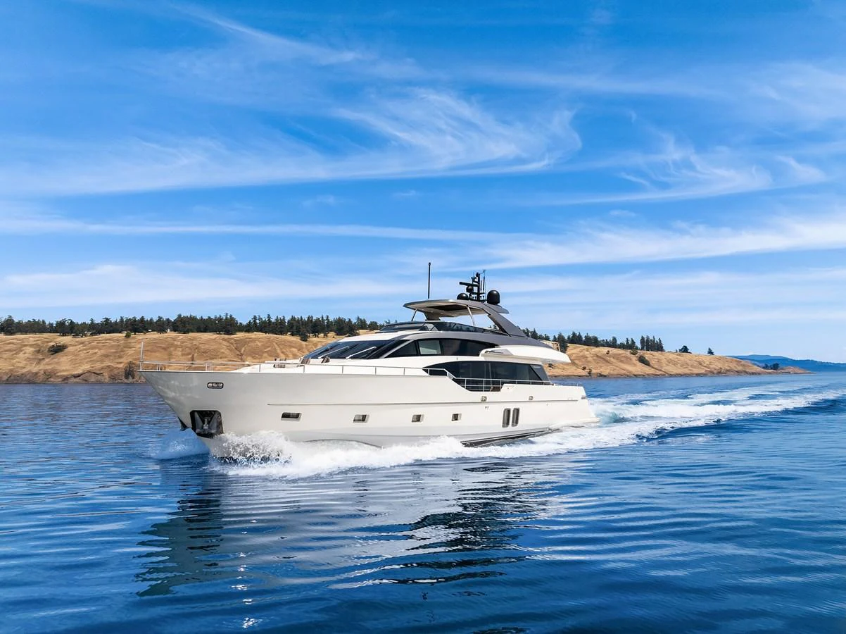 A sleek yacht cruises through calm waters under a clear blue sky. aboard ESSENZA Yacht for Sale