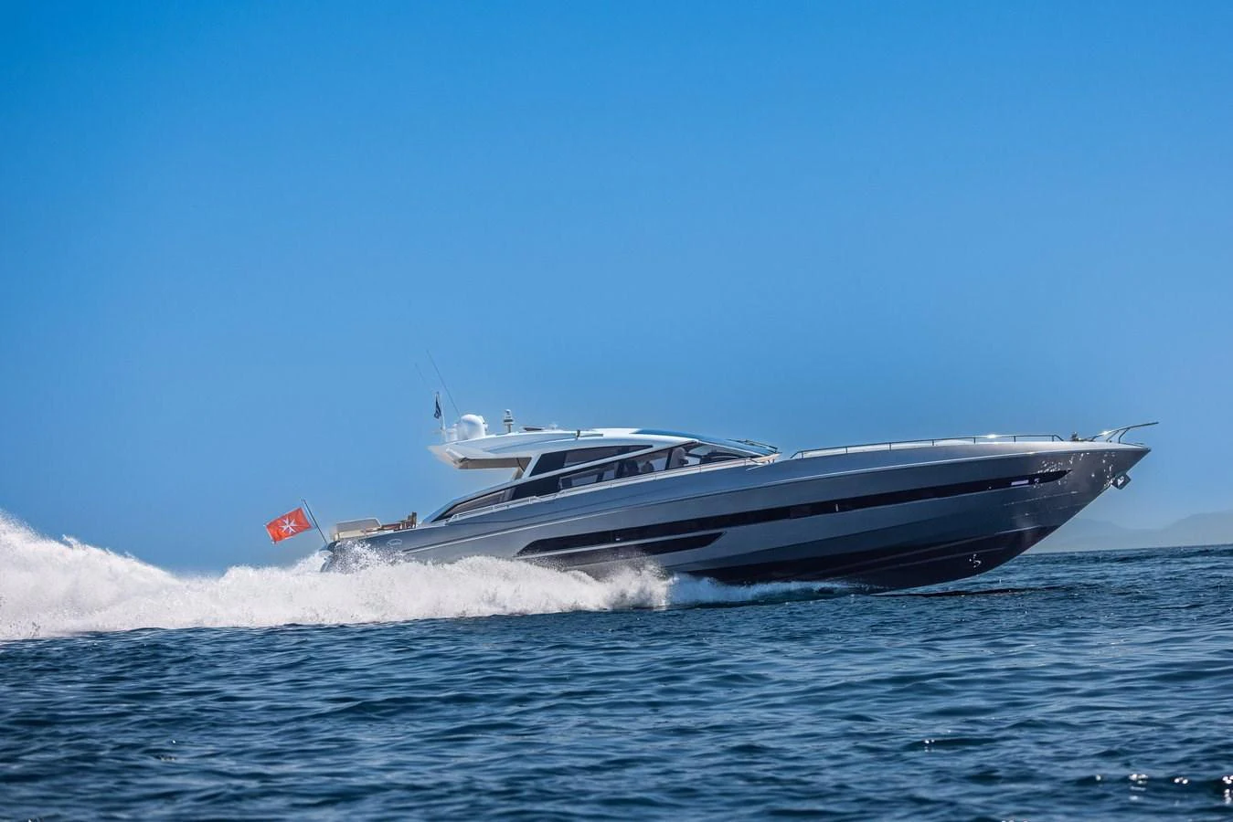 A sleek yacht cruises swiftly across the water under a clear blue sky. aboard LIONESS Yacht for Sale