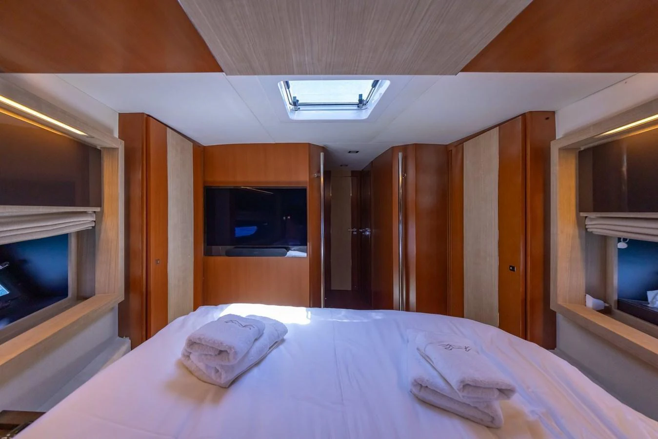The stateroom features a comfortable bed with neatly folded towels and ample natural light from the overhead hatch. aboard LIONESS Yacht for Sale