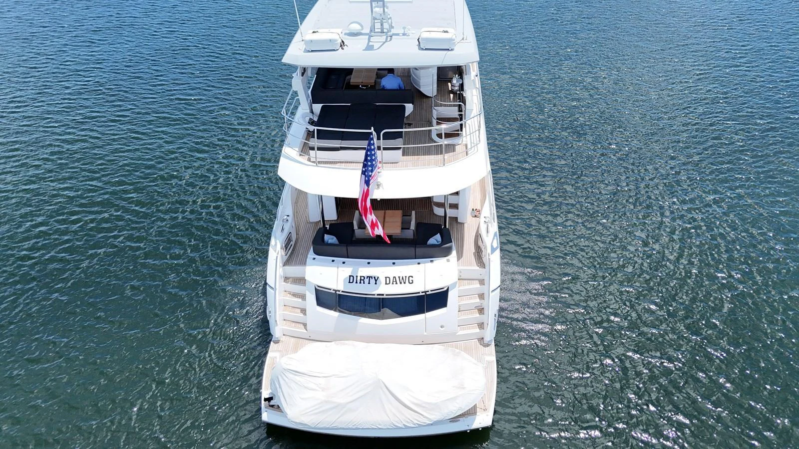 A luxurious yacht is anchored on calm waters, showcasing its spacious aft deck and elegant design. aboard DIRTY DAWG Yacht for Sale
