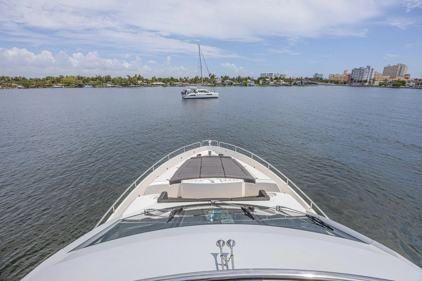The yacht's bow is seen from the deck, overlooking calm waters and a distant shoreline. aboard DIRTY DAWG Yacht for Sale