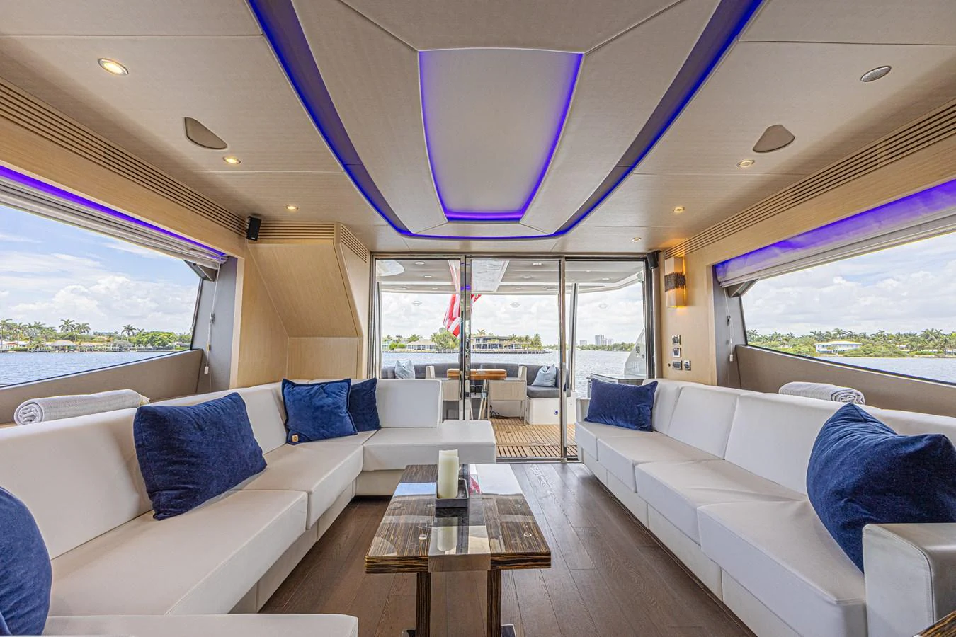 The salon features luxurious seating with blue accent pillows and panoramic windows offering stunning views. aboard DIRTY DAWG Yacht for Sale